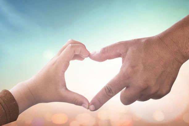 A parent and child making a heart shape with their hands